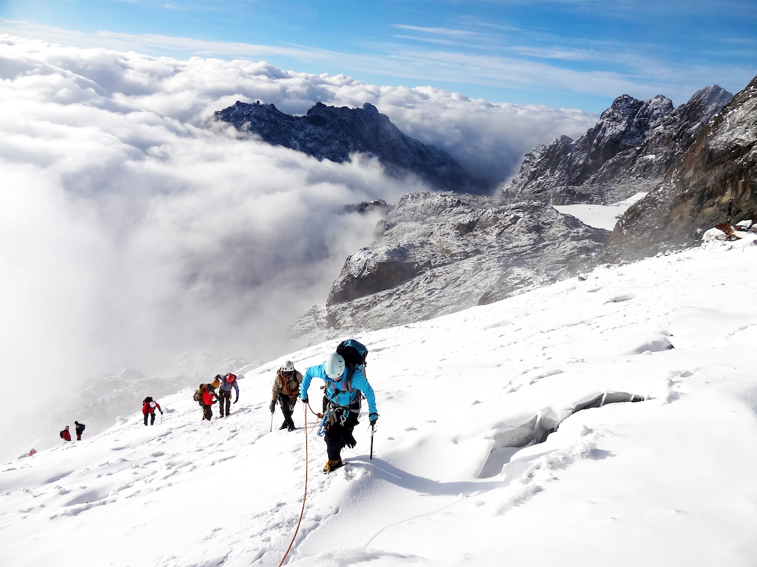 A roped team of climbers crossing the snow of the Margherita Glacier in the Rwenzori Mountains
